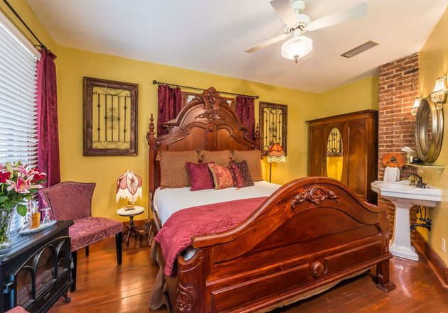 A bedroom with a large wooden bed and a sink.