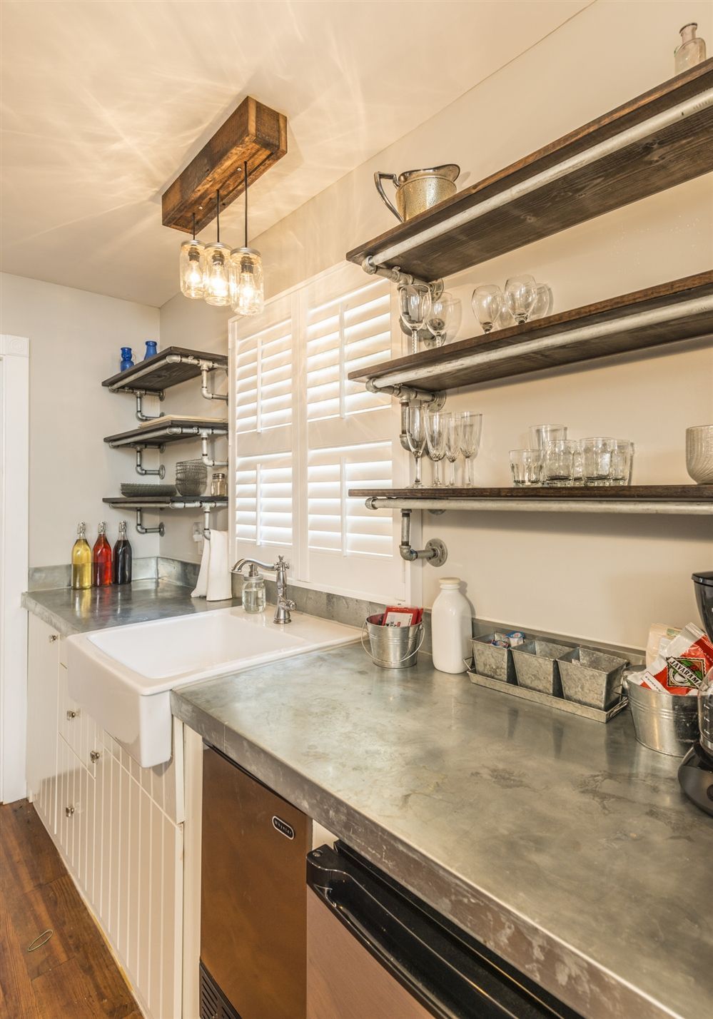 A kitchen with a sink , dishwasher , and shelves.
