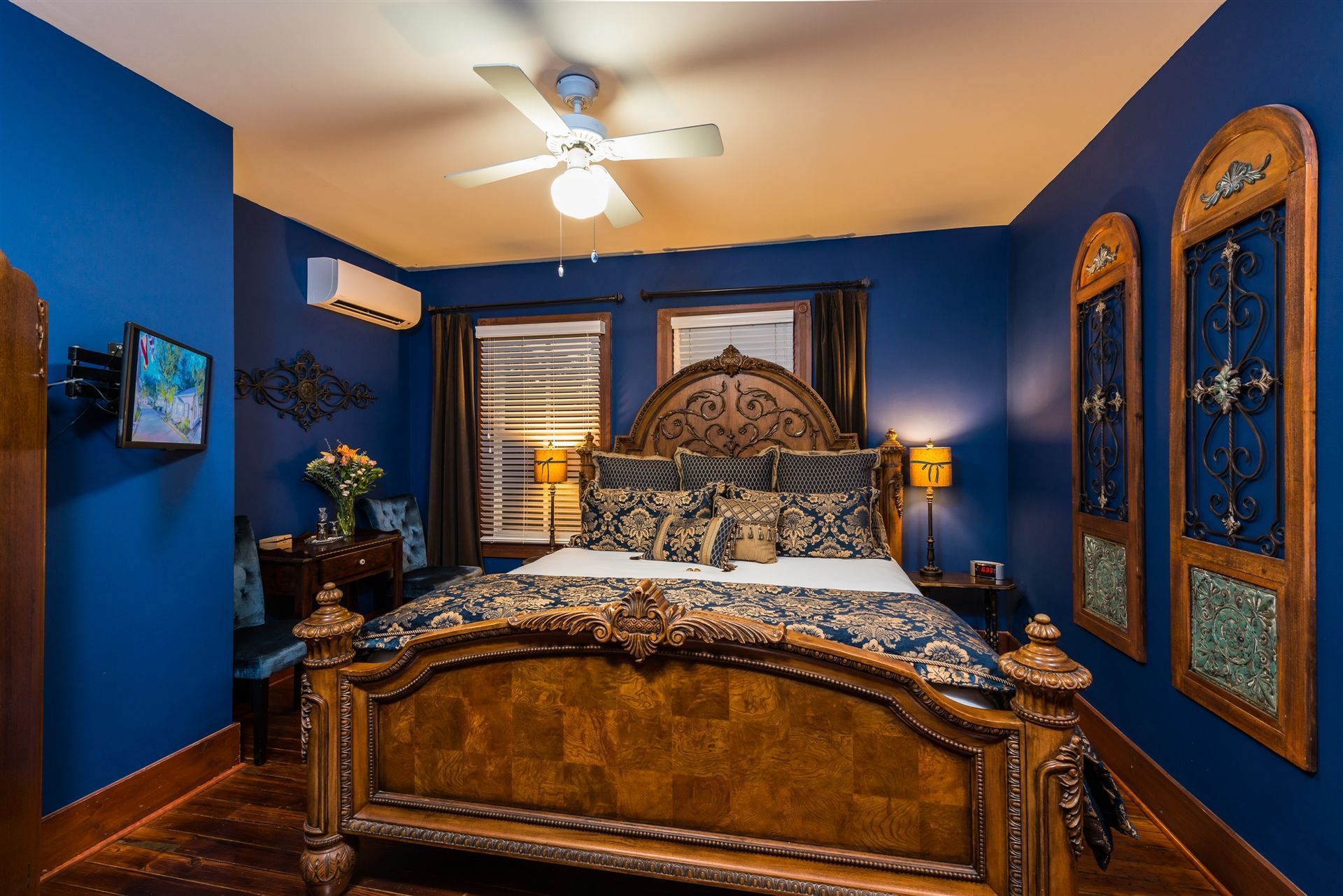 A bedroom with blue walls and a king size bed with a ceiling fan.