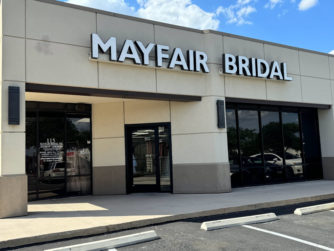 The front of a mayfair bridal store with a parking lot in front of it.