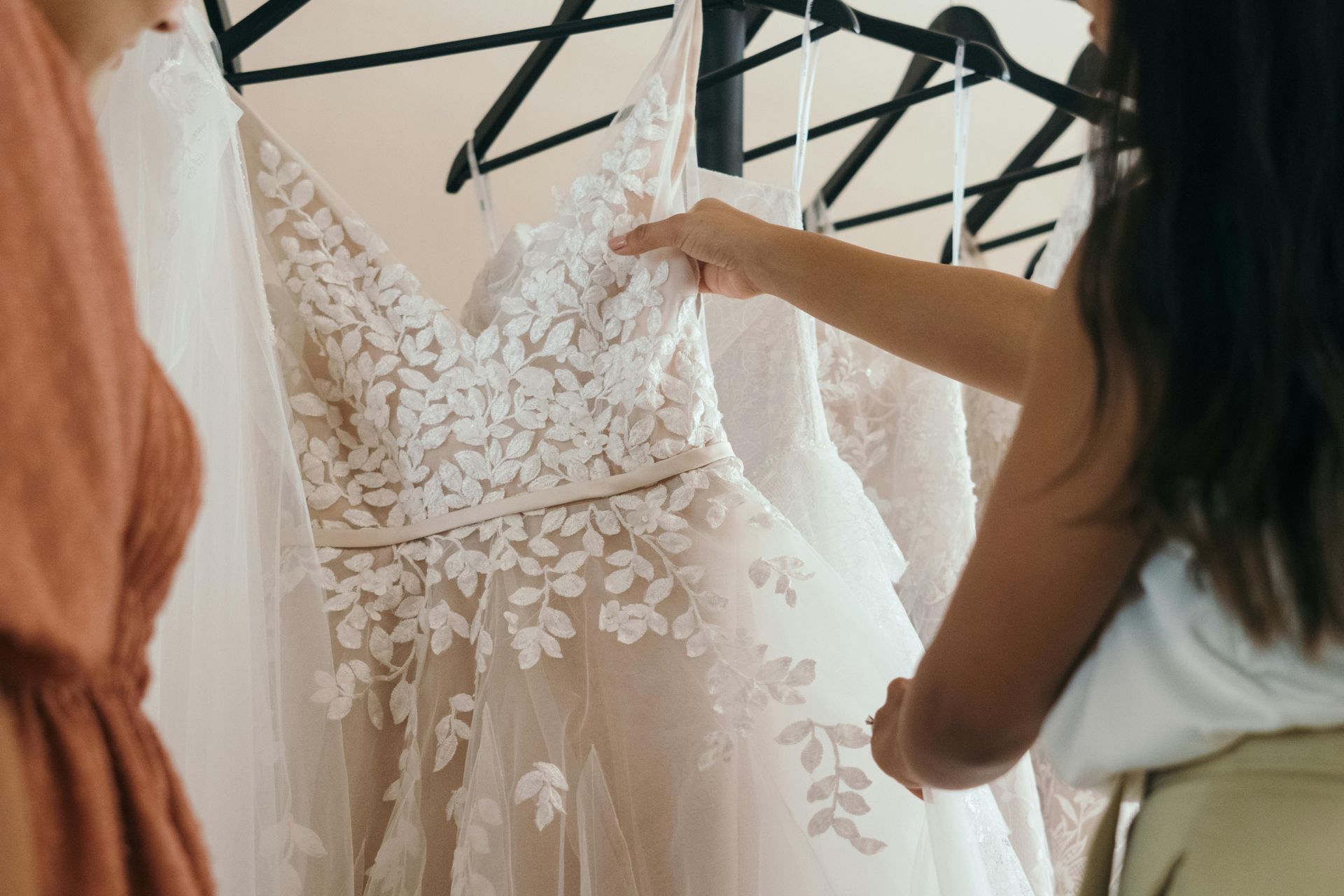 A woman is looking at a wedding dress hanging on a rack.
