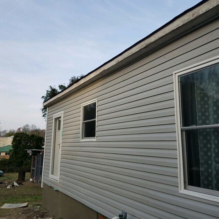 Close-up view of off-white horizontal vinyl siding meeting at an exterior corner trimmed with a vertical white post.