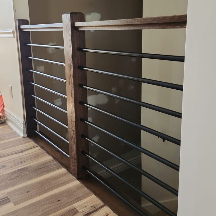 Modern interior railing featuring a dark wooden top rail and square post with horizontal black metal bars.