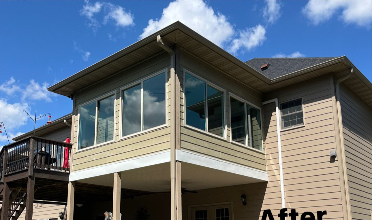 A gray stone bay window protrudes from a house wall built with multicolored, rectangular natural stones.