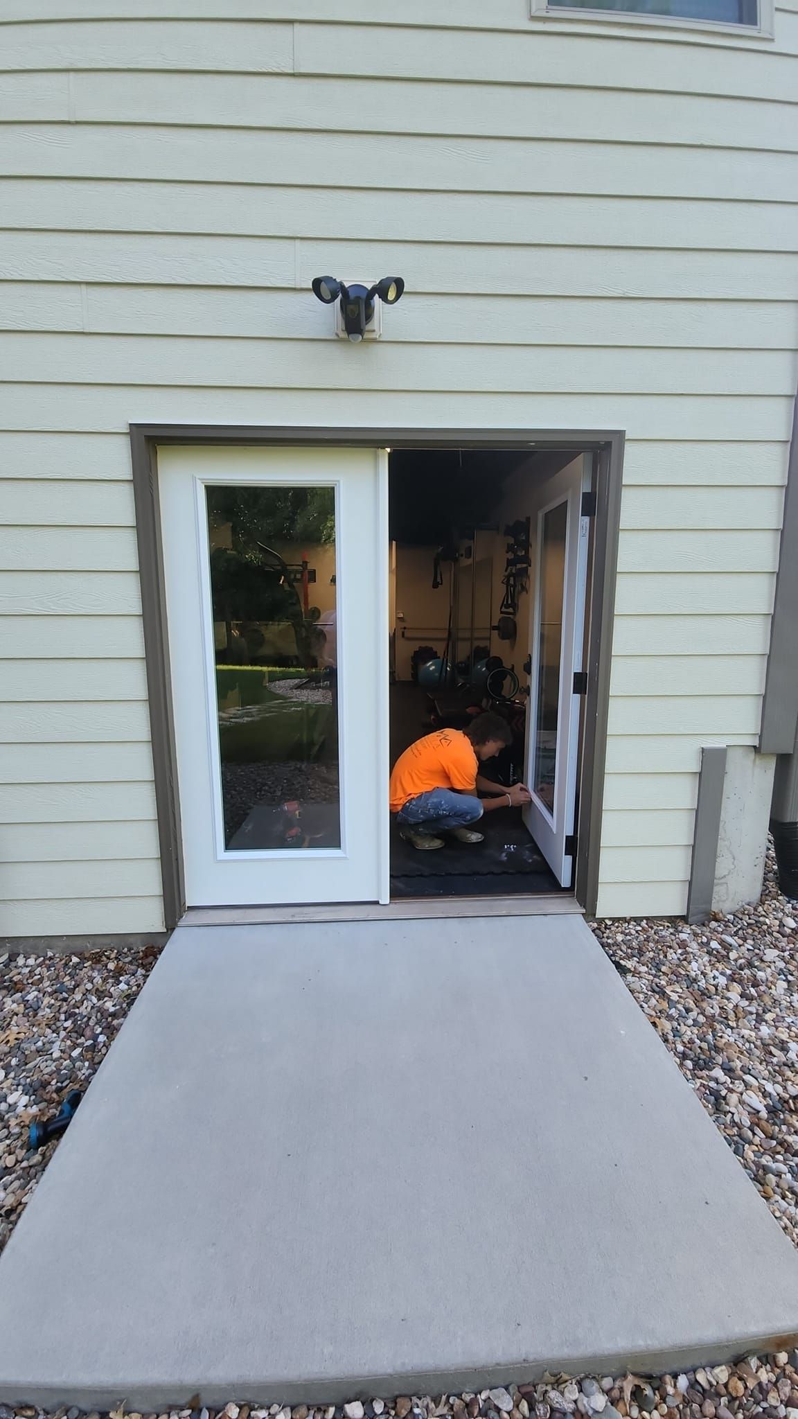 A bright sunroom with white walls, exposed brick pillars, tile flooring, and large windows overlooking a city skyline.