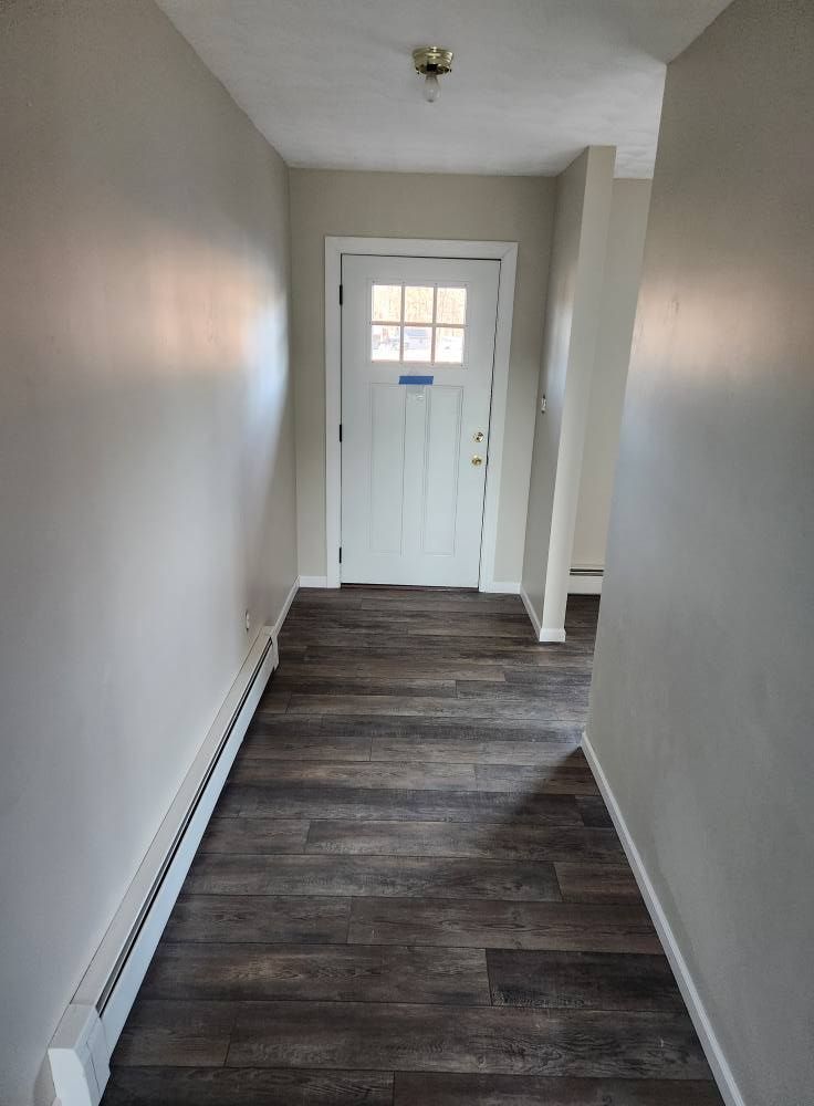 An unfinished wooden deck and gable-roof porch extension under construction attached to the back of a tan house.