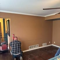 A small laundry room with off-white walls, dark wood-look flooring, wall-mounted wire shelving, and utility hookups.