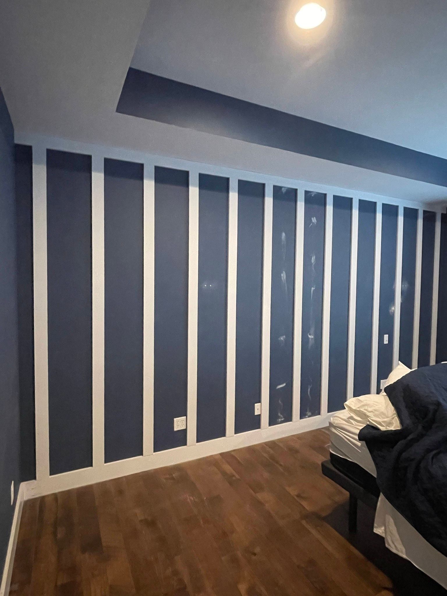 An interior view of a room under construction with unfinished drywall, exposed wooden door frames, and a white front door.