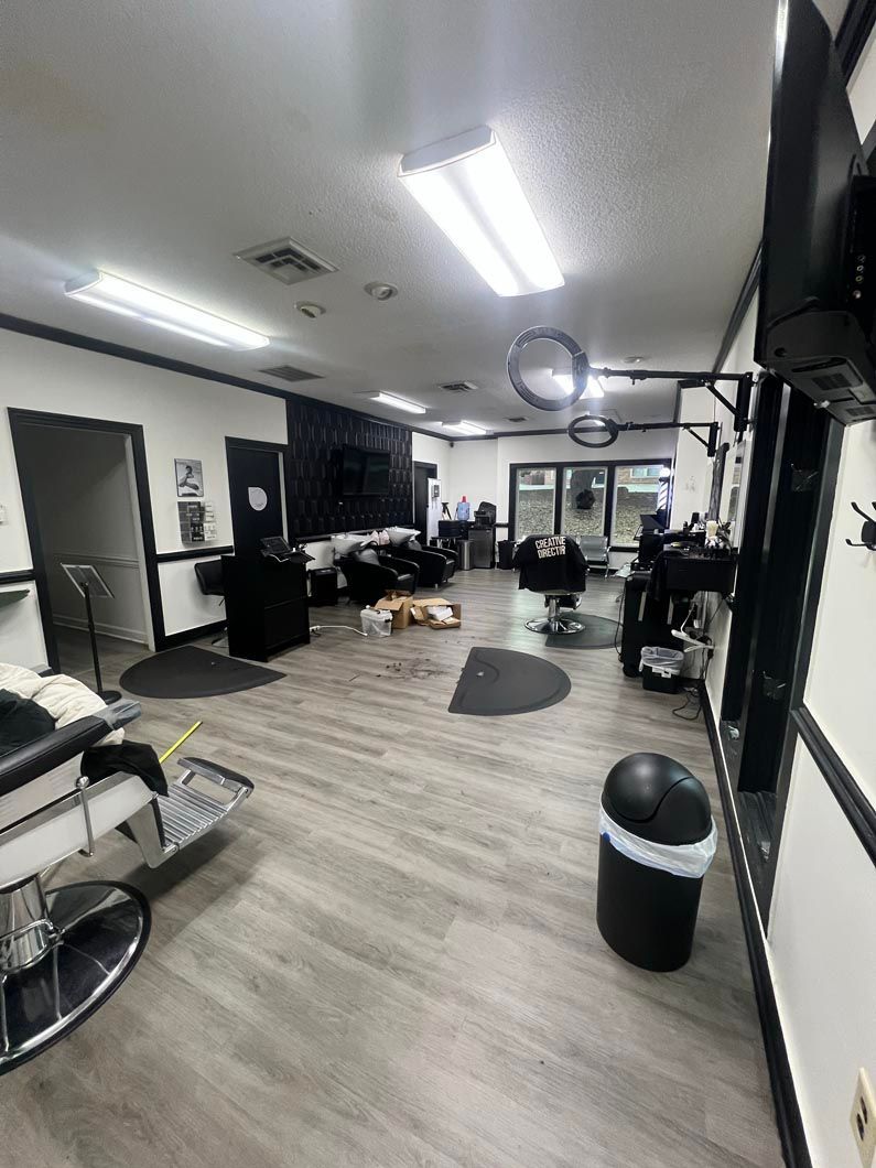 Barbershop interior with barber chairs, waiting area, and black and white decor.