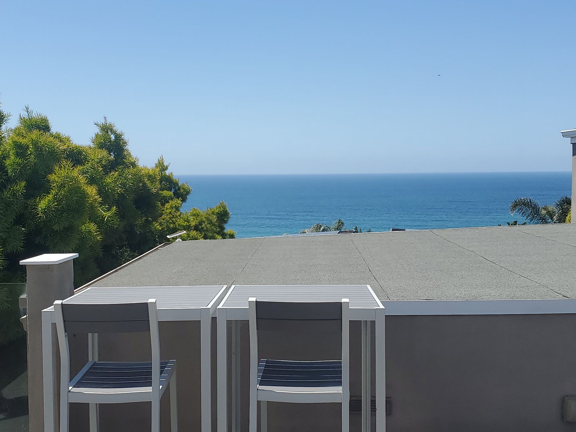 A table and chairs on a roof overlooking the ocean