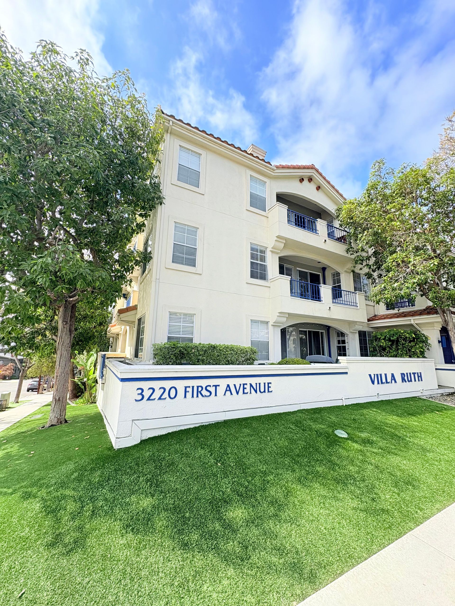 A large white apartment building with a sign in front of it.