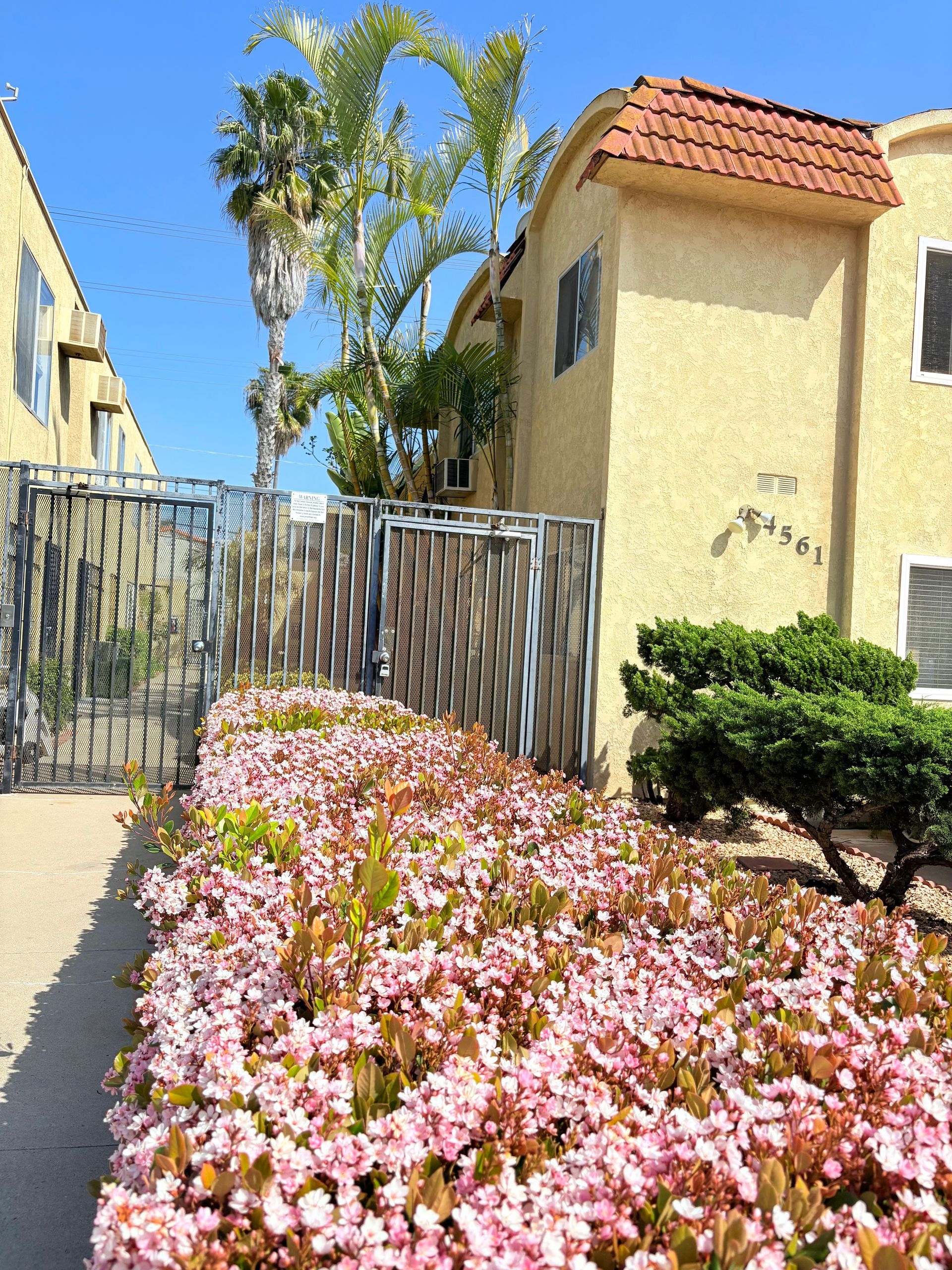 A house with a fence and flowers in front of it
