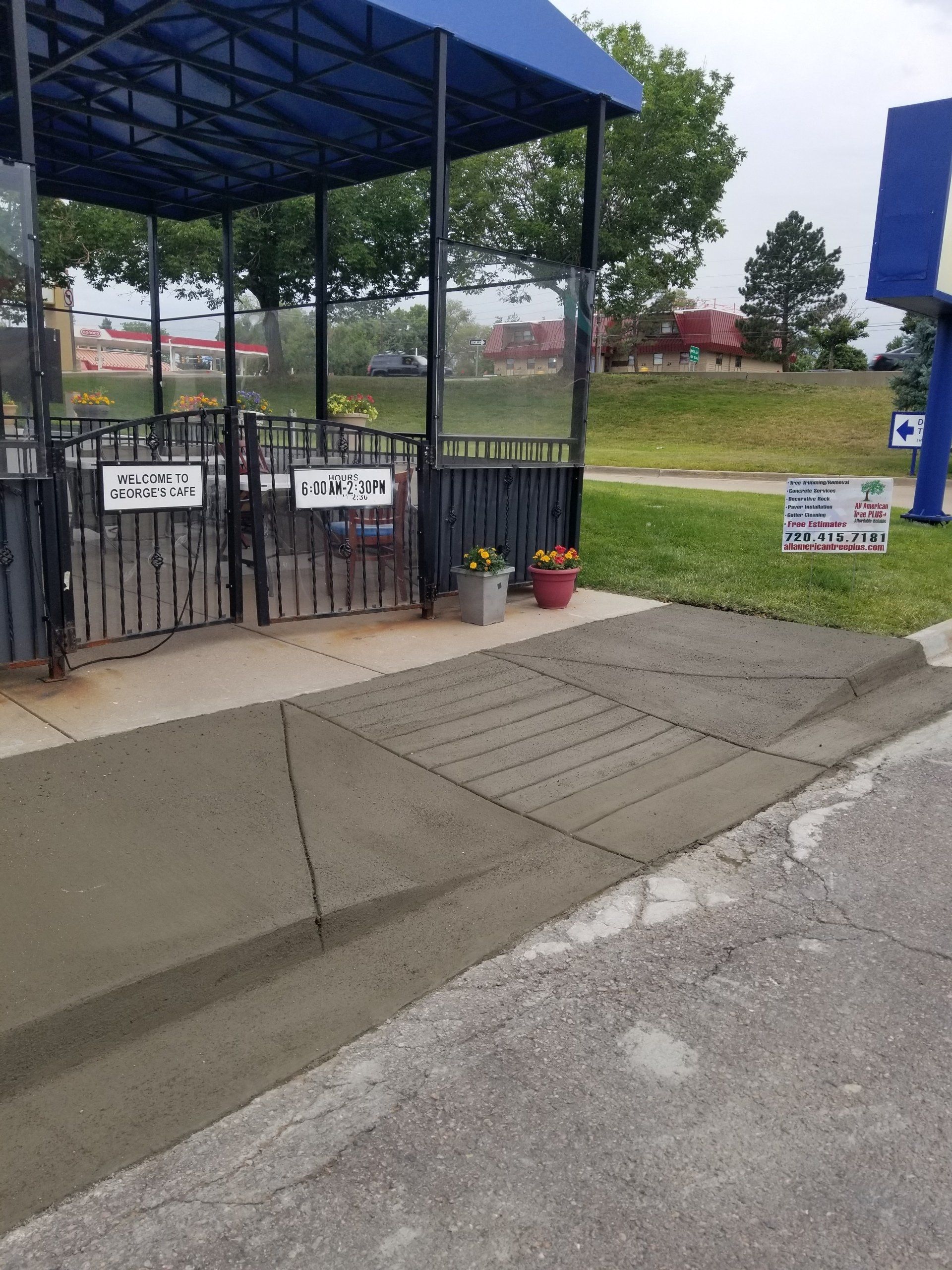 New concrete ramp with blue awning and black fence.