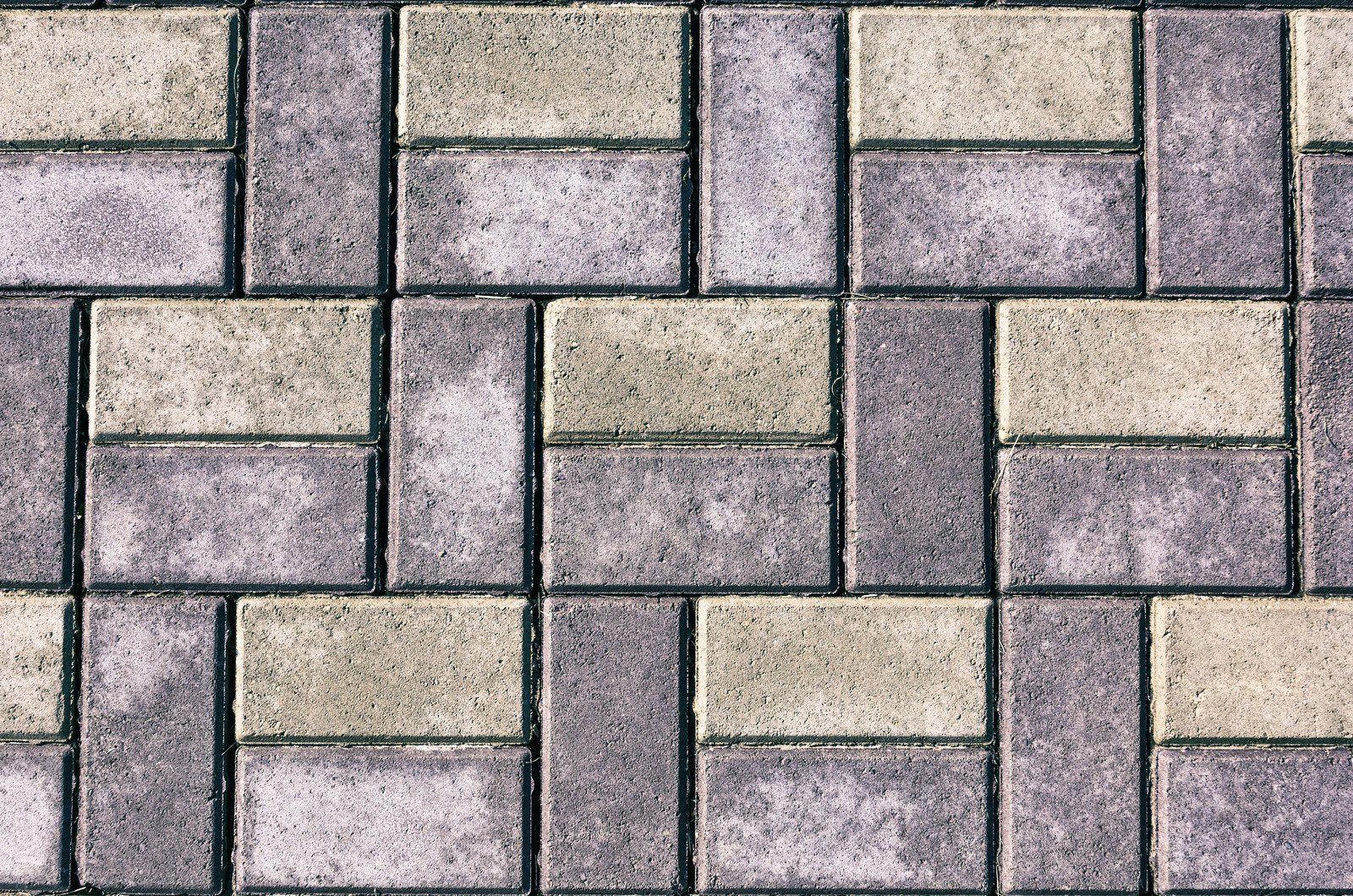 Gray and tan brick pavers in a repeating rectangular pattern.
