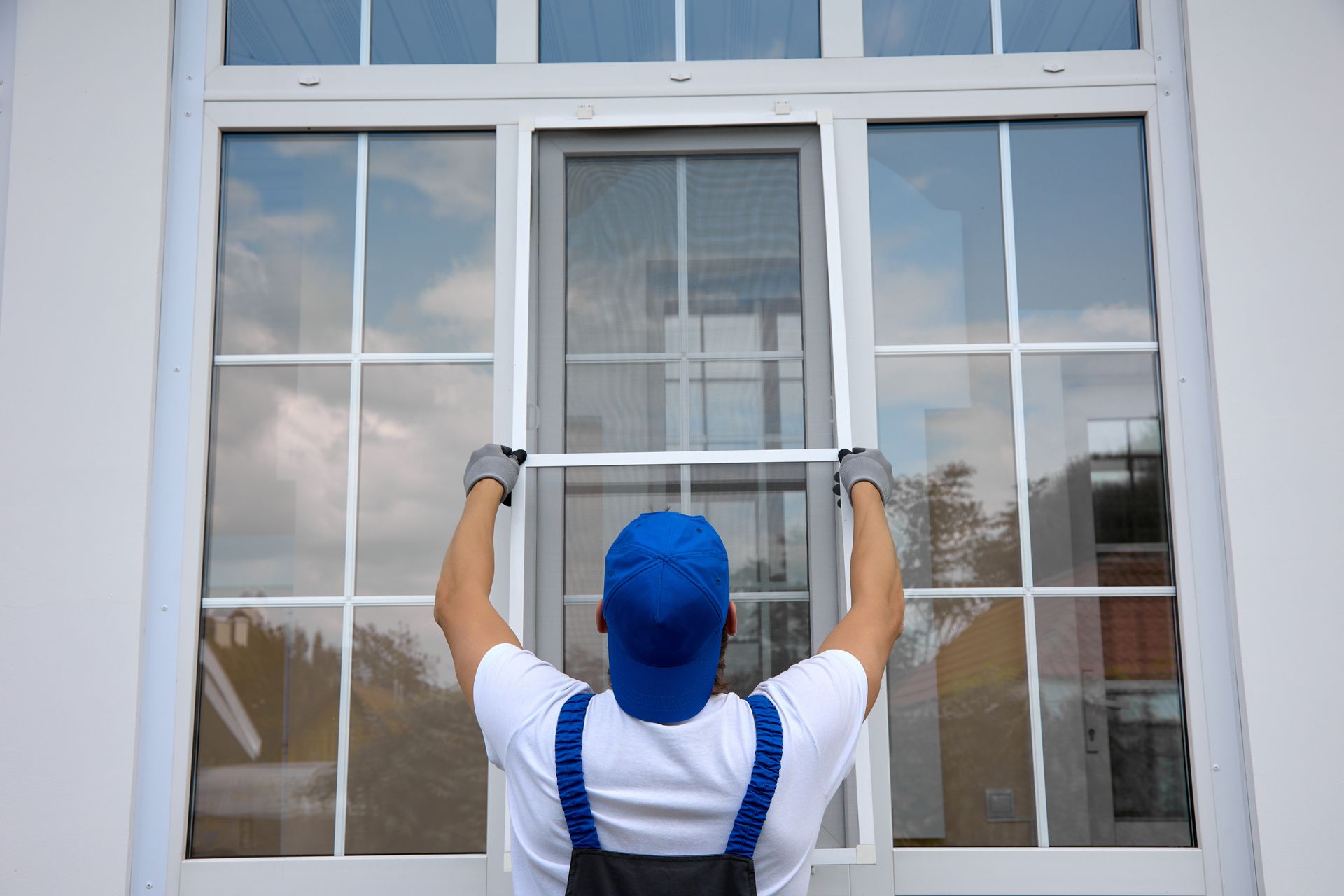 Window Installation — Person in blue hat and gloves installing a window screen on a white building in Gibsonia, PA
