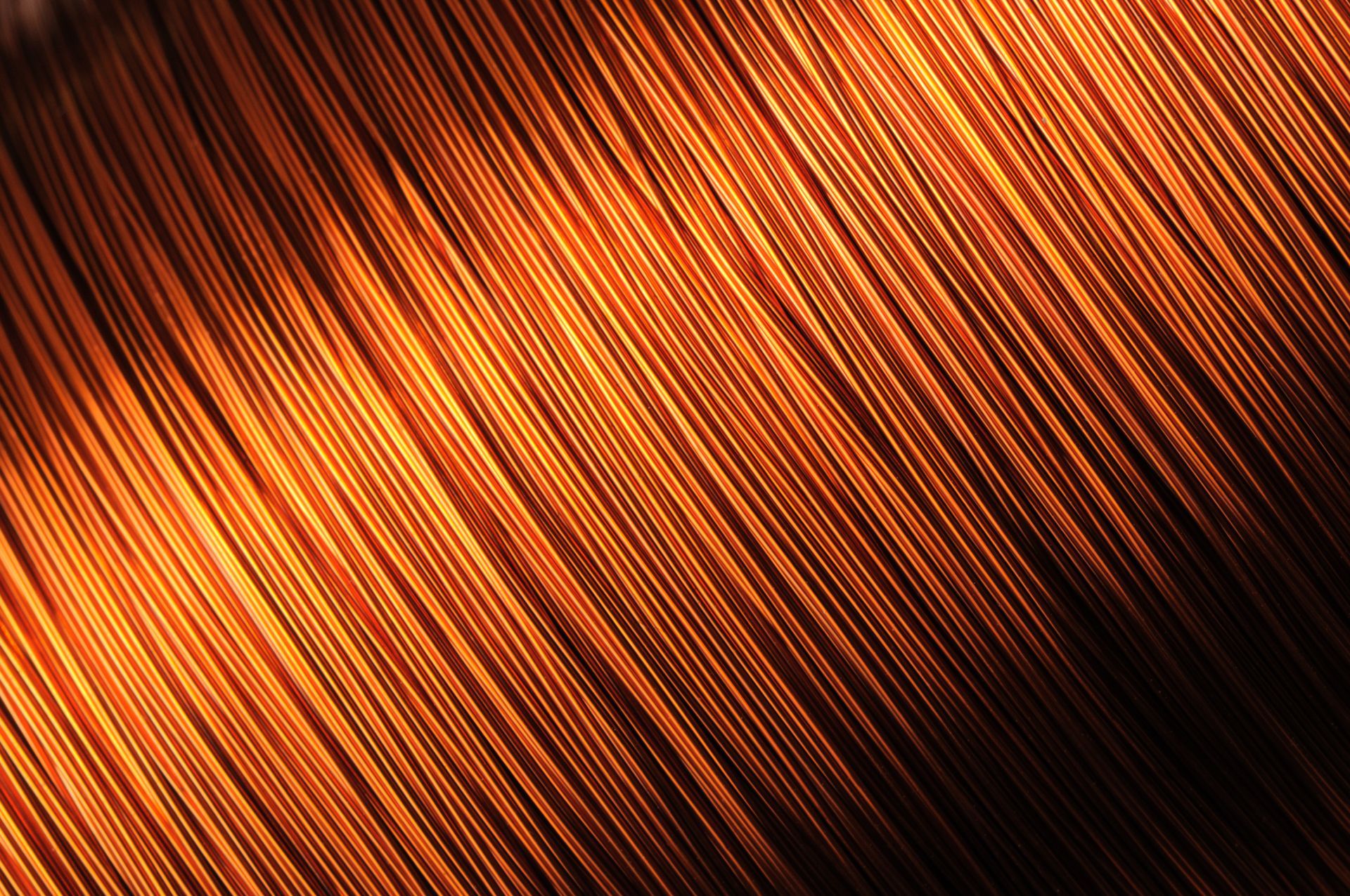 Primo piano di una bobina di filo di rame su uno sfondo nero.