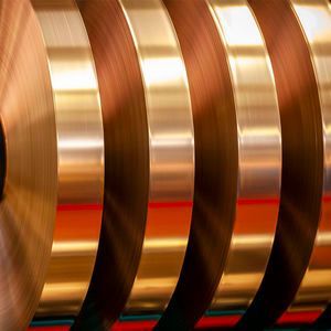 Una fila di rotoli di lamina di rame disposti uno sopra l'altro su un tavolo.