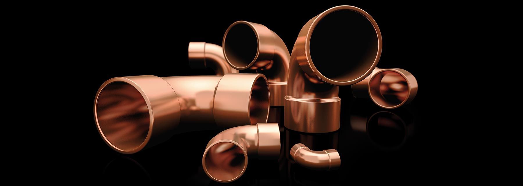 Un mucchio di tubi di rame sono posizionati uno sopra l'altro su una superficie nera.