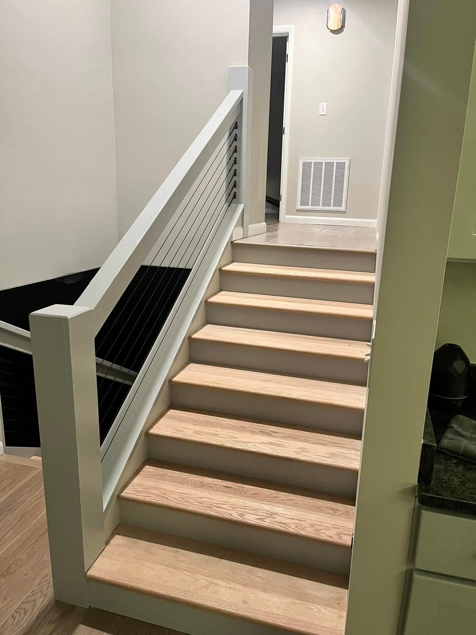Staircase with light-colored steps and a white railing with a perforated metal panel.  The hallway is visible in the background.
