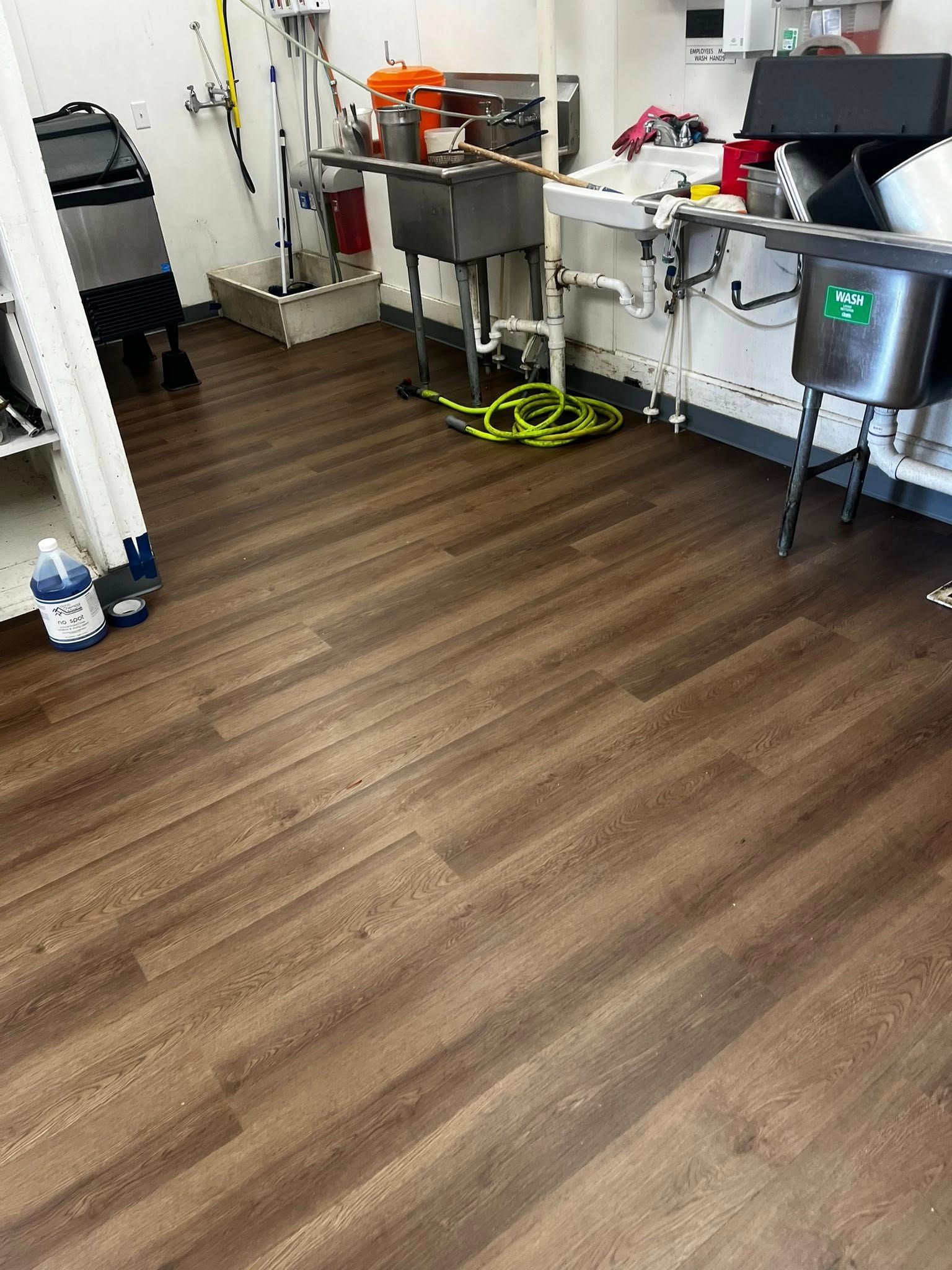 Brown wood-look flooring in a room with industrial sinks and equipment.