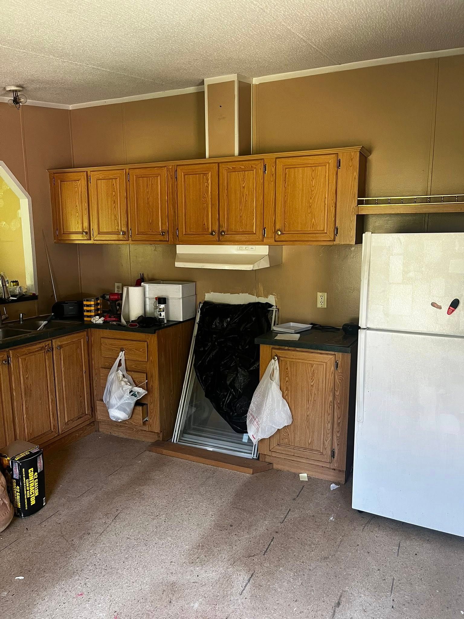 Kitchen with brown cabinets, refrigerator, and a covered opening.