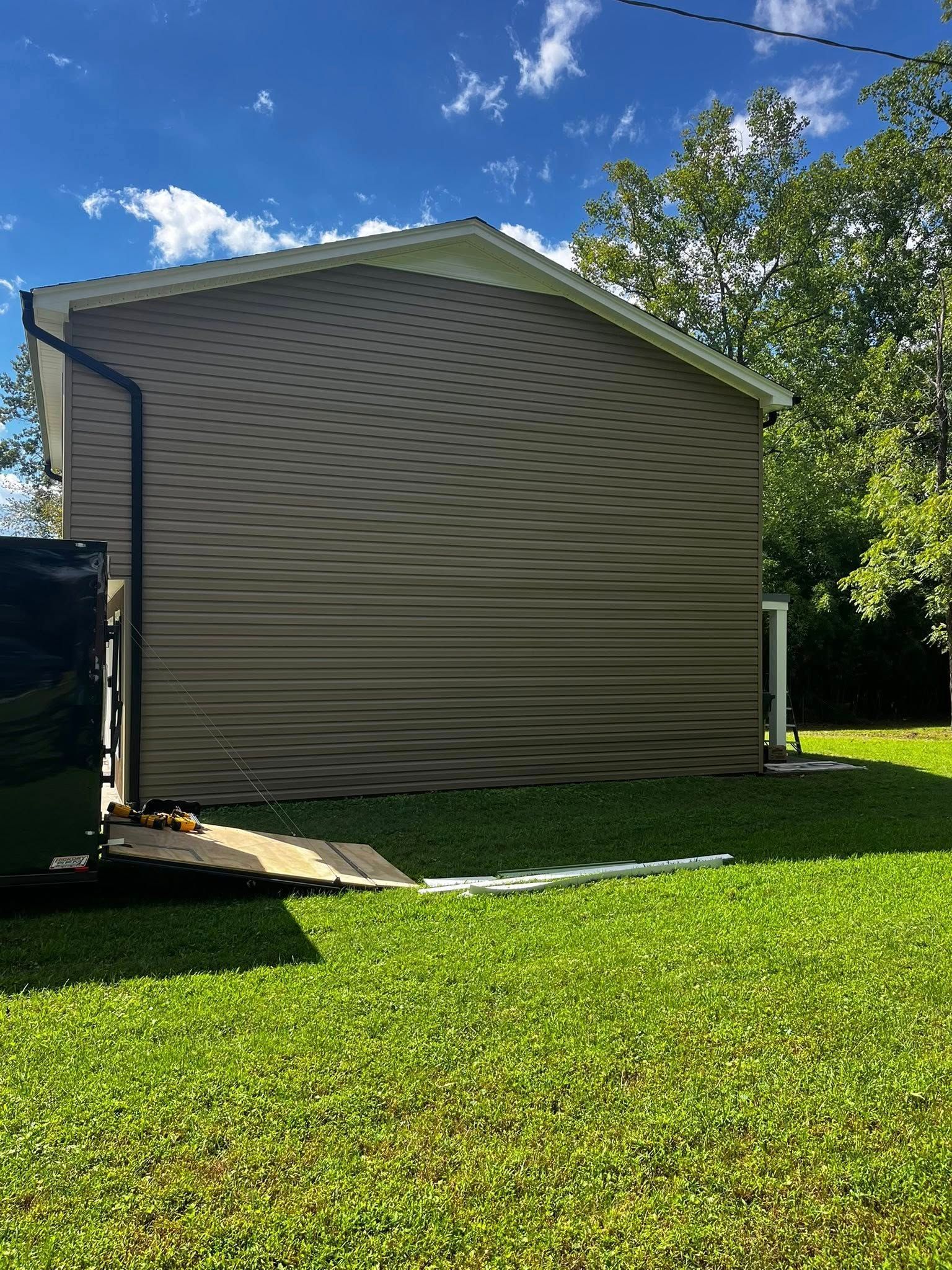 Side of a house with wavy siding, green grass, and blue sky.