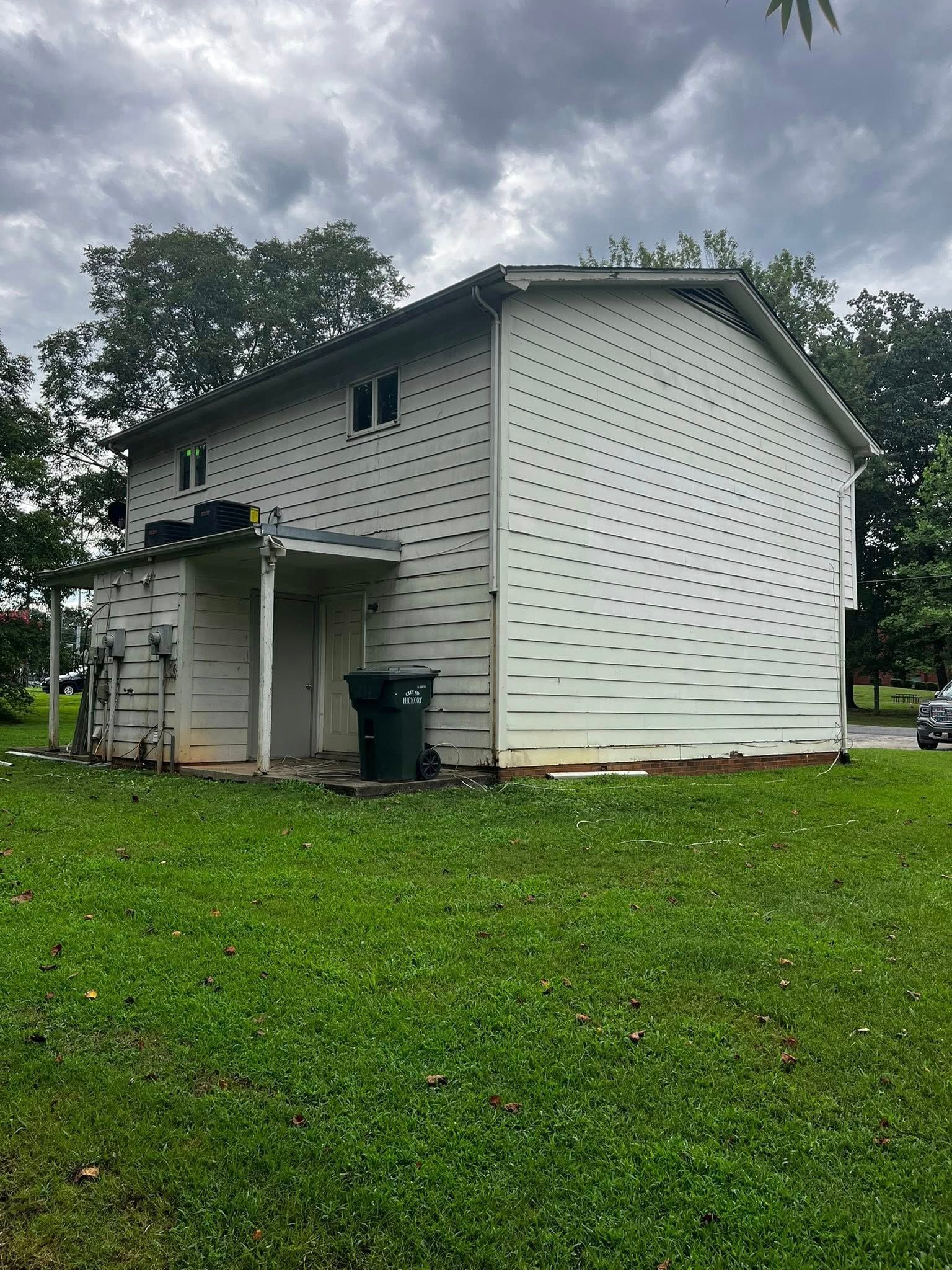 Two-story white house with black polka-dot pattern on siding. Green lawn and cloudy sky in background.