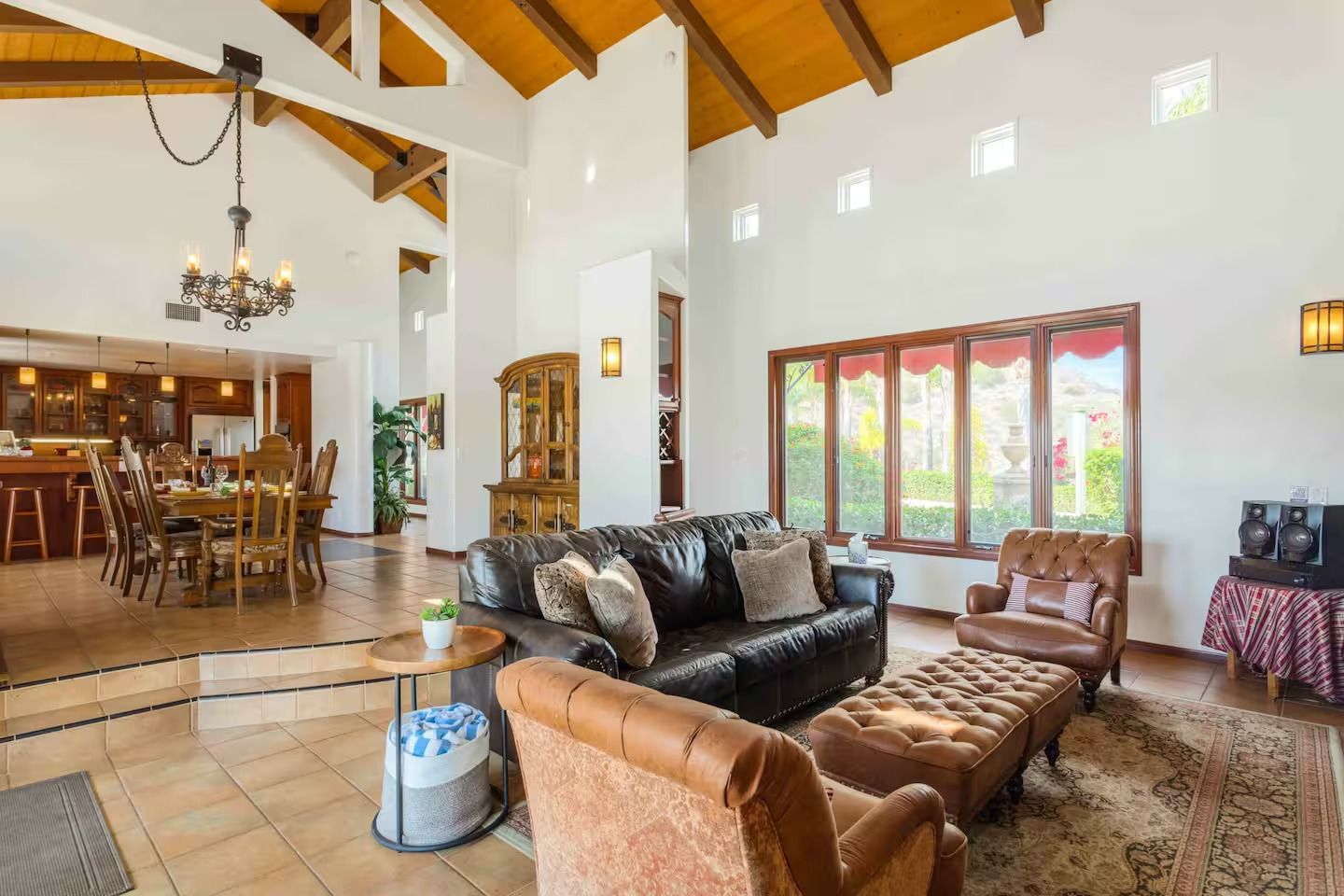 Spacious living room with high ceilings, leather furniture, and a dining area visible in the background.