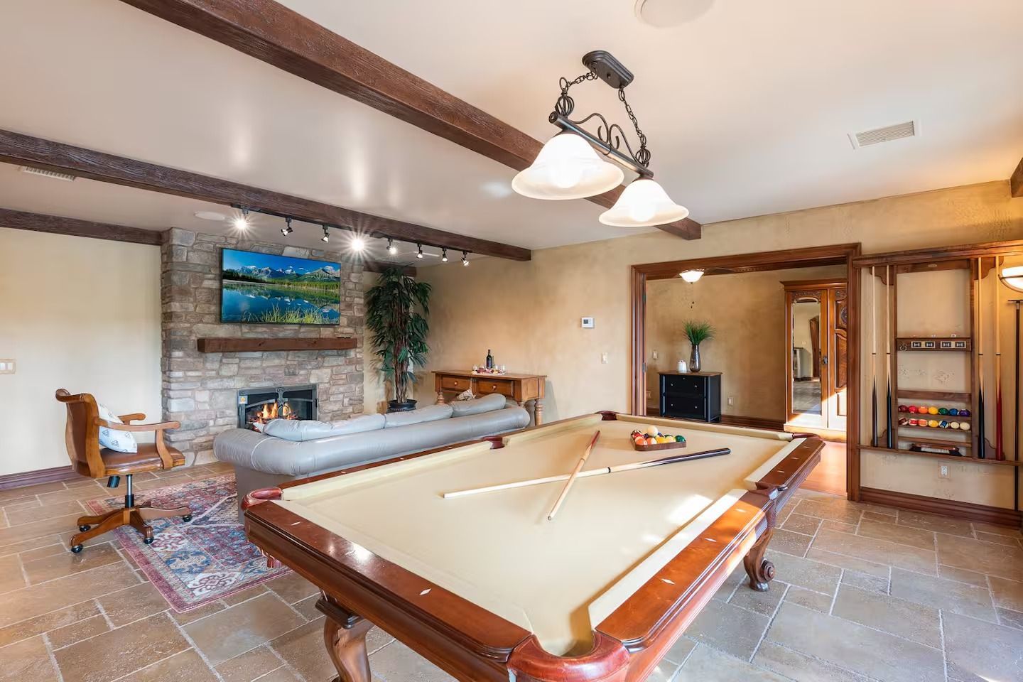 Pool table in a game room with fireplace, couch, and cabinets.
