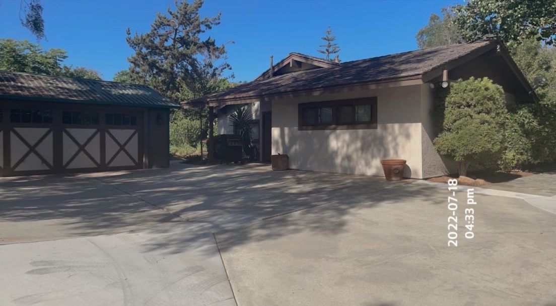Tan house with dark roof and attached garage on a sunny day.