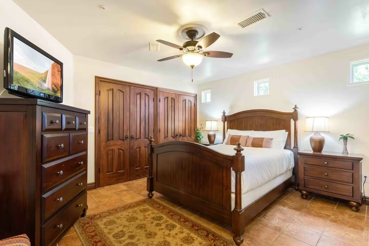 Bedroom with wooden furniture, including bed, dresser, and closet. Brown, tan, and white color palette.