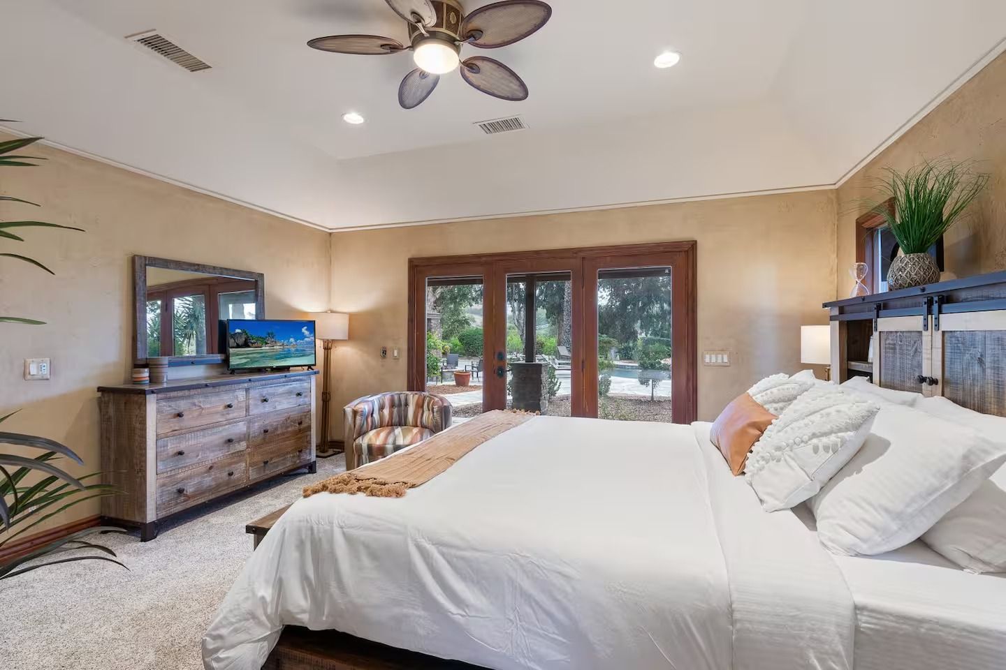 Bedroom with large bed, wooden furniture, and glass doors opening to the outdoors.