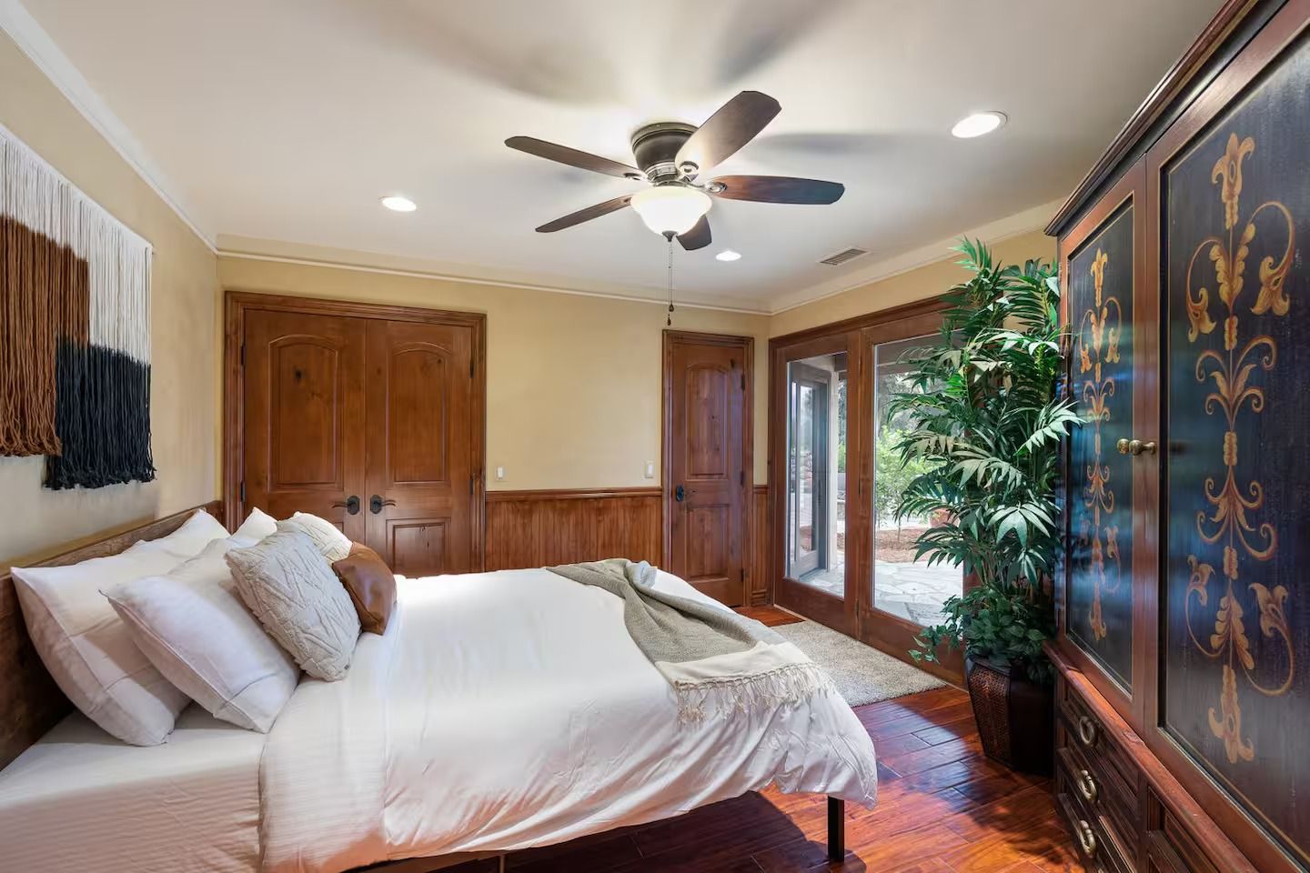 Bedroom with wooden furniture, bed with white bedding, and a large plant.