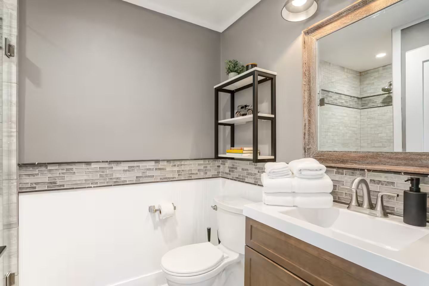Bathroom with white sink, toilet, gray walls, and rustic mirror.