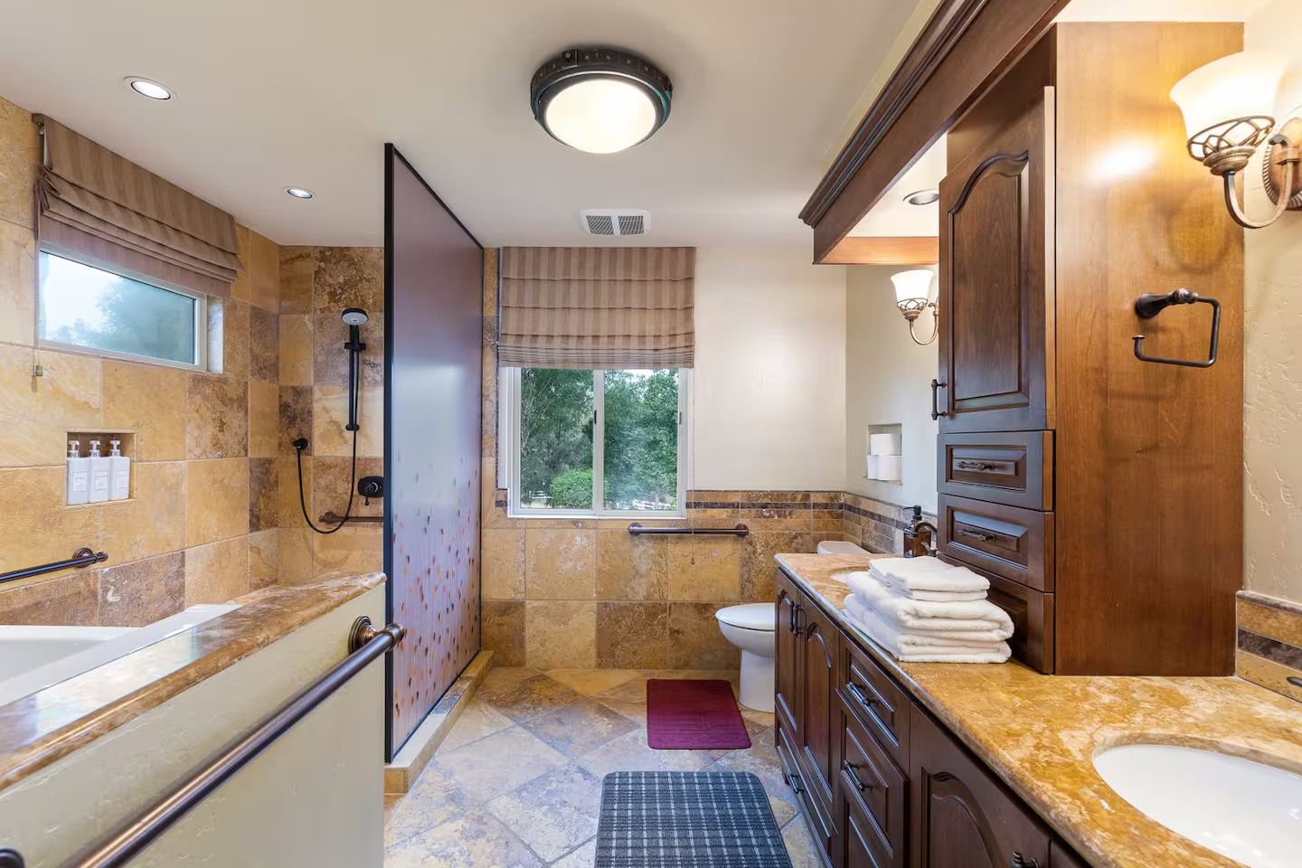 Bathroom with travertine tile, dark wood cabinets, and a walk-in shower.