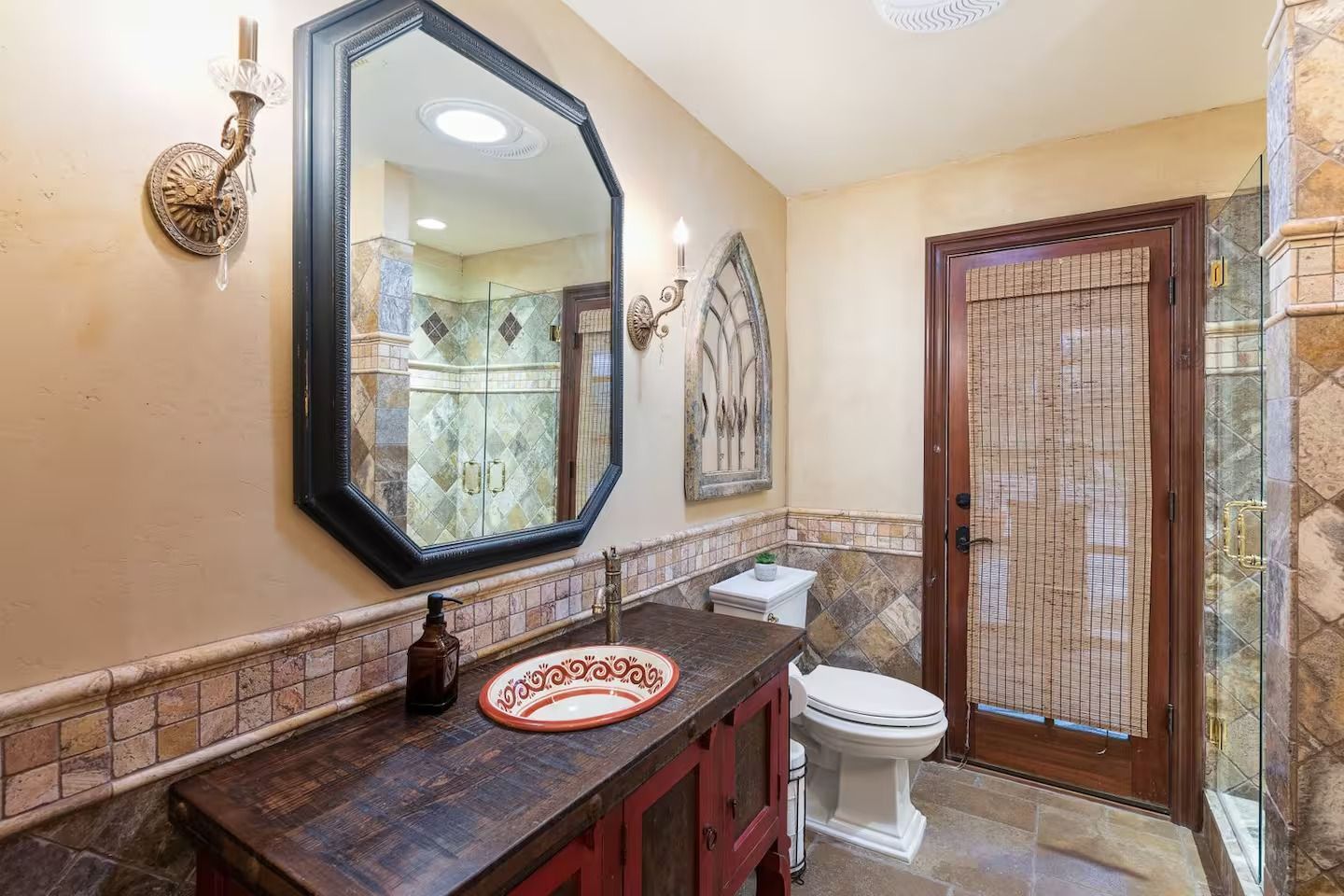 Bathroom with antique wood vanity, octagon mirror, and patterned tile accents.