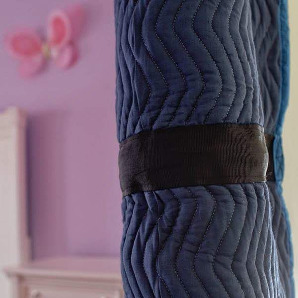 A purple wall with a butterfly on it is behind a blue blanket