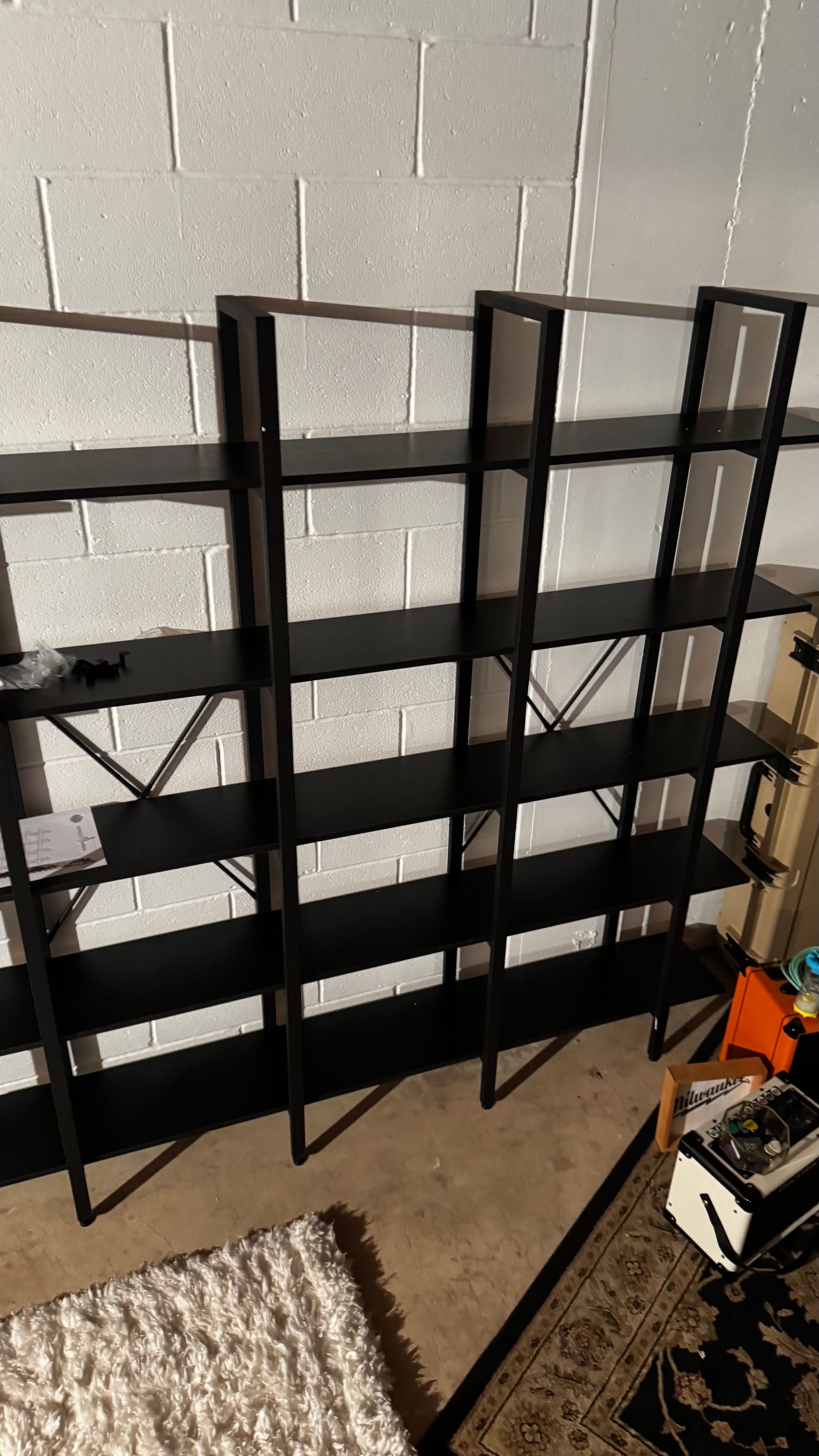 A black bookshelf is sitting in a room next to a rug.