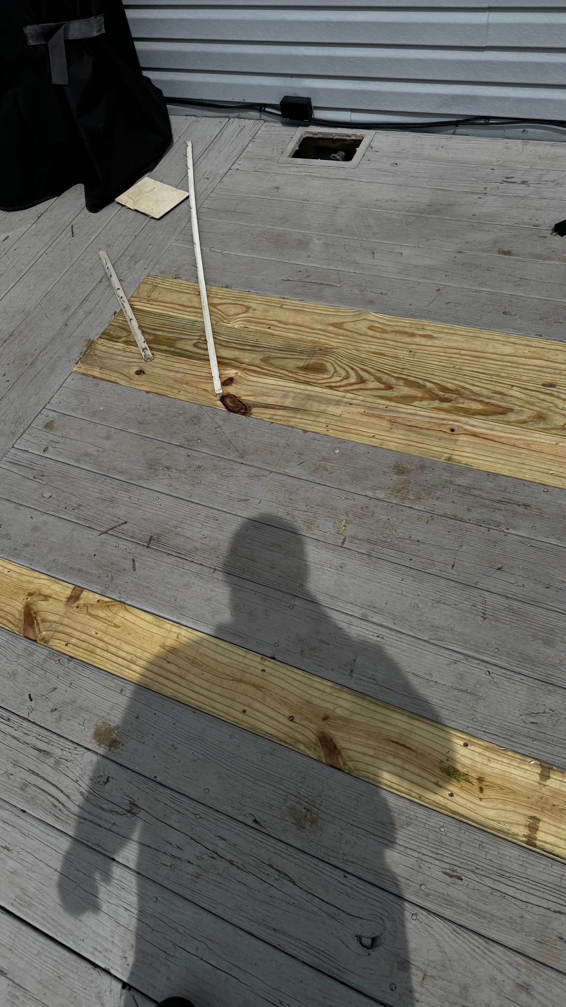 A person 's shadow is cast on a wooden deck.