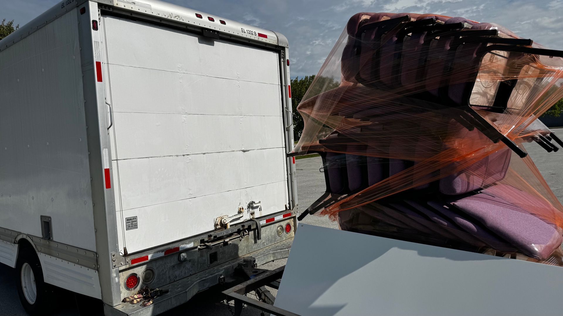 A white truck is parked next to a stack of boxes.