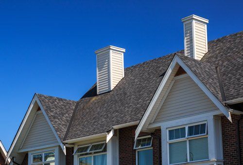 A row of houses with chimneys on the roofs against a blue sky.