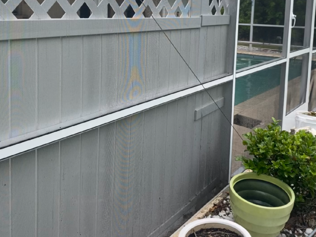 A cleaned fence with a screened in porch and potted plants in front of it - Port Charlotte, FL - MD Pressure Cleaning & Soft Wash