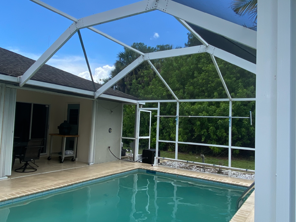 A swimming pool in a cleaned screened-in patio in front of a house - Port Charlotte, FL - MD Pressure Cleaning & Soft Wash