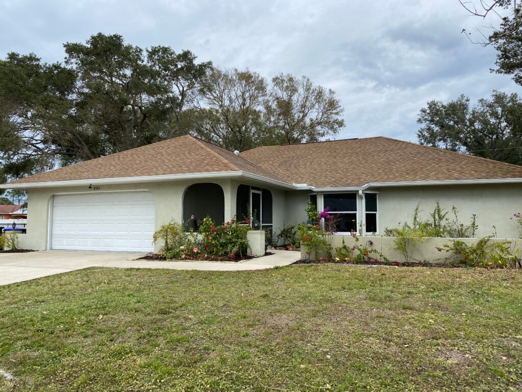 A white house with a cleaned brown roof and a white garage door - Port Charlotte, FL - MD Pressure Cleaning & Soft Wash