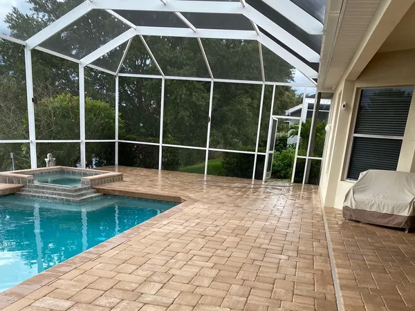 A screened in patio after cleaning with a swimming pool in the background - Port Charlotte, FL - MD Pressure Cleaning & Soft Wash