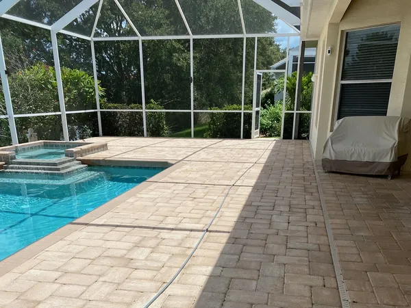 A screened in swimming pool with a brick patio - Port Charlotte, FL - MD Pressure Cleaning & Soft Wash