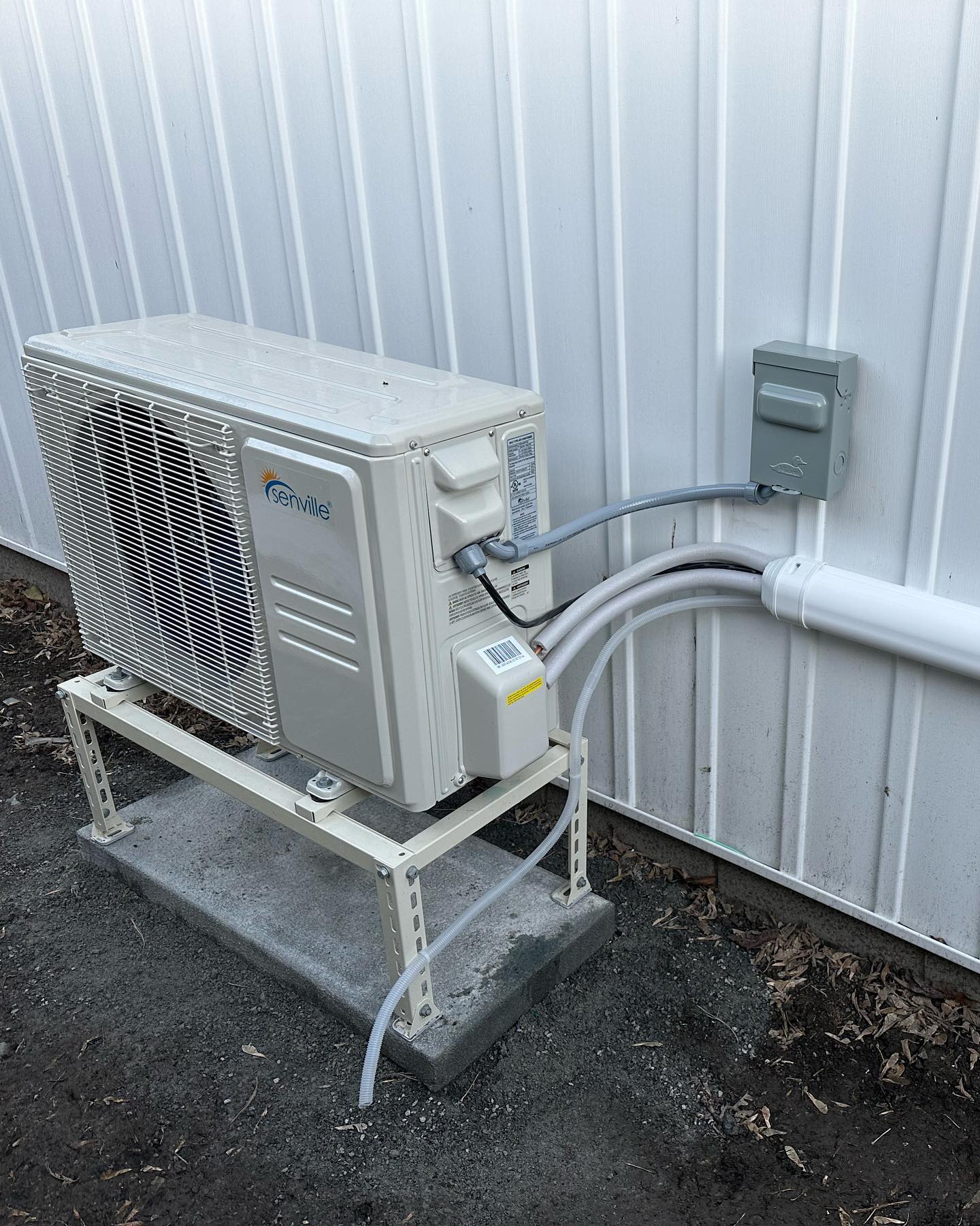 A white air conditioner is sitting on a metal stand next to a white wall.