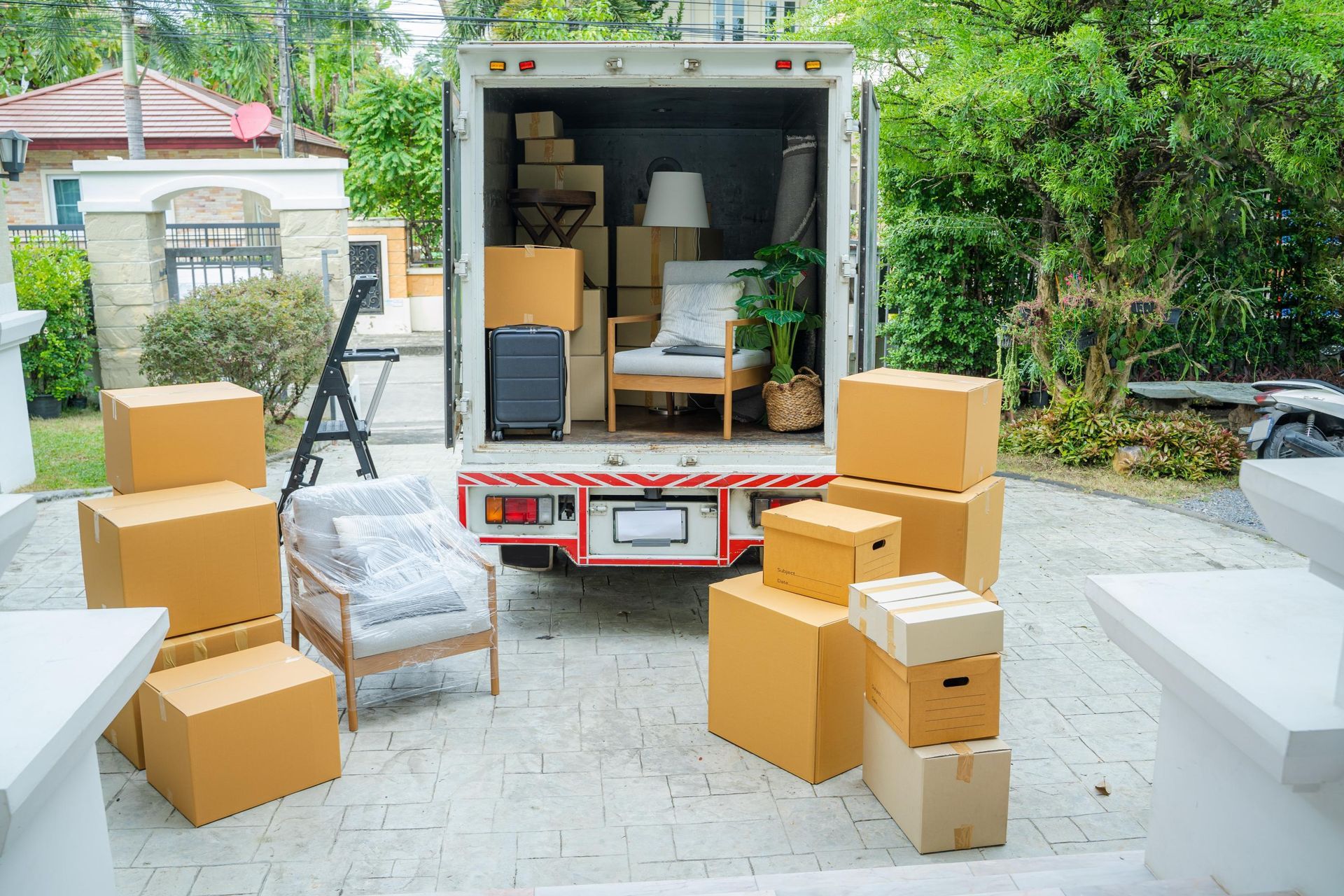 Moving truck loaded with boxes and furniture in front of a house.