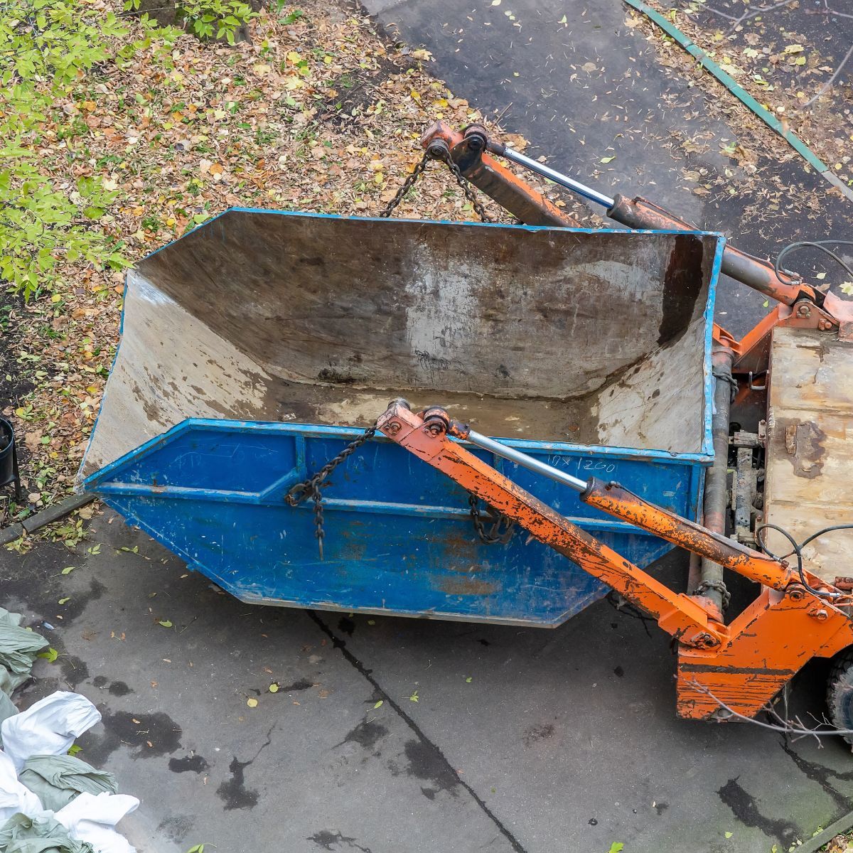 A blue dumpster is sitting on the side of the road