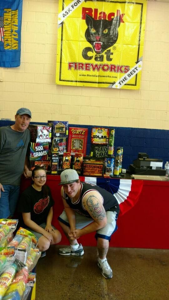 A group of people standing in front of a sign that says black cat fireworks
